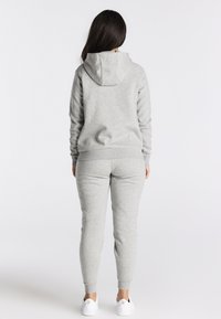 Grijze sweatshirt- en joggingbroekset, gemaakt van zachte stof. Voorzien van een capuchon, geribbelde manchetten en een slank ontwerp met subtiele merkopdruk.