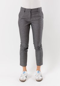 Pantaloni grigi a quadri con vestibilità sartoriale, dotati di tasche frontali, vita bassa e che si affusolano fino alla caviglia, indossati con sneakers bianche.