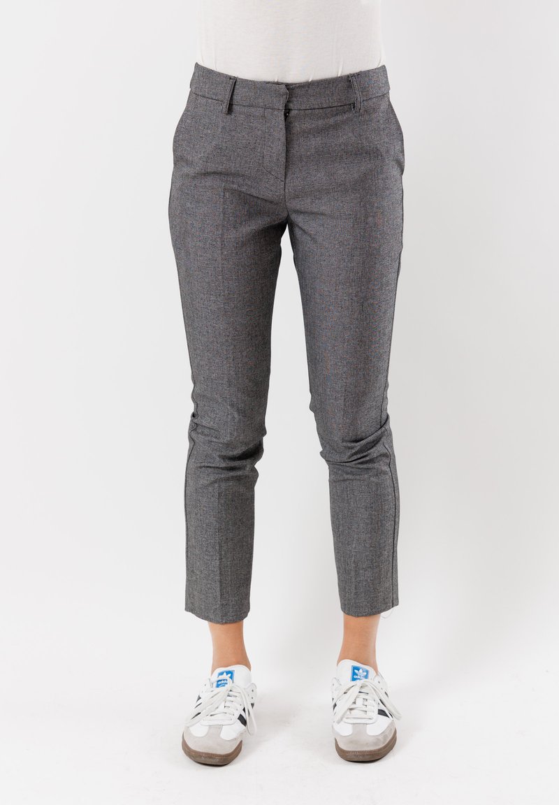 Pantaloni grigi a quadri con vestibilità sartoriale, dotati di tasche frontali, vita bassa e che si affusolano fino alla caviglia, indossati con sneakers bianche.