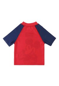 Camiseta roja de manga corta con mangas raglán en azul marino; presenta un sutil diseño impreso de un personaje en la parte posterior. Textura suave, tejido ligero.