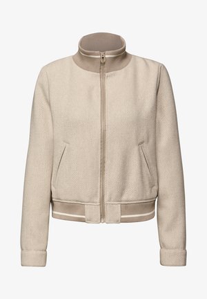 Veste légère beige en tissu texturé, col montant, fermeture éclair à l'avant et deux poches plaquées. Poignets et taille côtelés.