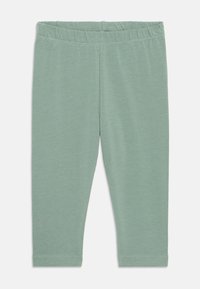 Leggings in cotone verde con vita elastica, caratterizzati da una texture liscia e un design aderente, che si estendono fino a metà polpaccio.