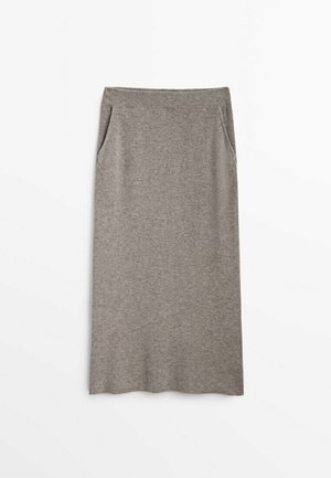 Jupe midi grise en tissu doux et extensible. Dotée d'une ceinture ajustée et de deux poches latérales. Texture lisse avec un motif côtelé.