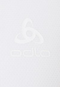 Weißer Stoff mit einer strukturierten Oberfläche und einem geprägten Odlo-Logo. Das Design ist minimalistisch und einfarbig.