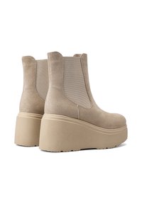 Stivali plataforma in suede beige con pannelli laterali elasticizzati, punta arrotondata e tacco spesso a cuneo, dotati di suola testurizzata per una maggiore aderenza.