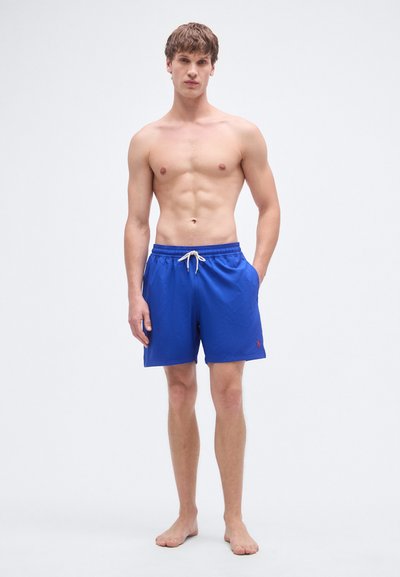 Μπλε μαγιό σορτς με ρυθμιζόμενο κορδόνι στη μέση, πλαϊνές τσέπες και ένα μικρό κόκκινο λογότυπο στο τελείωμα. Κατασκευασμένο από ελαφρύ, λείο ύφασμα.