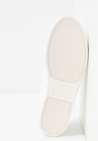 Semelle de sneaker blanche en caoutchouc texturé, avec des rainures horizontales pour la traction. Le bord intérieur affiche une empreinte de taille 37.