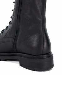 Zwarte leren enkelboot met een gladde textuur, versterkte stiksels, een zijknop en een robuuste rubberen zool met profiel.