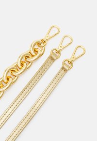 Złocony łańcuszek o gładkim wykończeniu w połączeniu z dwoma złotymi metalowymi paskami z teksturowanym detalem i obrotowymi zapięciami.