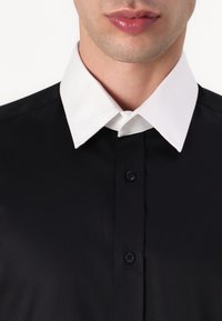 Svart skjorte med hvit spiss krage, med en jevn tekstur og knappelukking, som viser et klassisk design.