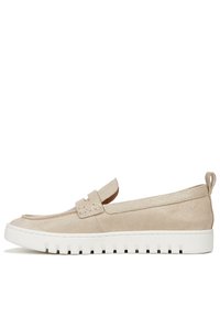 Chaussure slip-on en daim beige avec une tige texturée, semelle plate et accent tressé sur la sangle. Dispose d'une languette au talon pour un enfilage facile.
