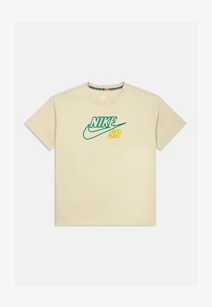 Bež pamučna majica s kratkim rukavima s tim zelenim i žutim "Nike SB" logotipom. Okrugli izrez, kratki rukavi i standardni kroj.
