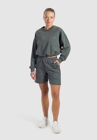Grauer, kurz geschnittener Sweatshirt und passende Shorts, beide aus glattem Stoff gefertigt. Das Sweatshirt verfügt über einen Rundhalsausschnitt und einen elastischen Saum.