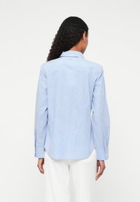 Blue and white striped button-up shirt with a classic collar, long sleeves, and a curved hem. Made of lightweight fabric, featuring button details.