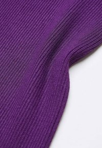 Gros plan sur un tissu en tricot côtelé violet avec une texture visible et des lignes verticales serrées sur fond blanc.