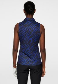 Sleeveless shirt featuring a blue and black tiger stripe pattern, with a collared neckline and smooth fabric texture.