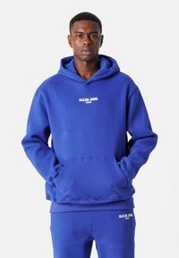 Sudadera azul real hecha de tejido suave con un bolsillo canguro en la parte delantera. Presenta "SIXTH JUNE PARIS" en letras blancas en el pecho.