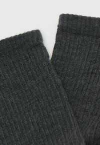 Calcetines de color gris oscuro con una textura suave y un patrón de tejido ajustado. Los puños están ligeramente doblados, mostrando la elasticidad de la tela.