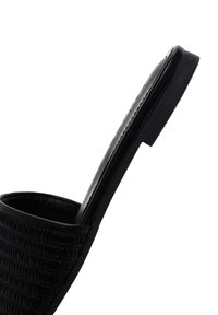 Mule nera con tacco alto, frontale texturizzato e rigato, profilo elegante e suola liscia. Il design presenta una forma e una finitura minimalista.