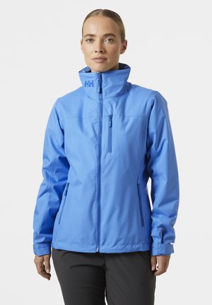 Chaqueta de color azul claro fabricada en material impermeable, con cuello alto, cremallera frontal y bolsillos laterales. Textura suave con acentos mínimos.