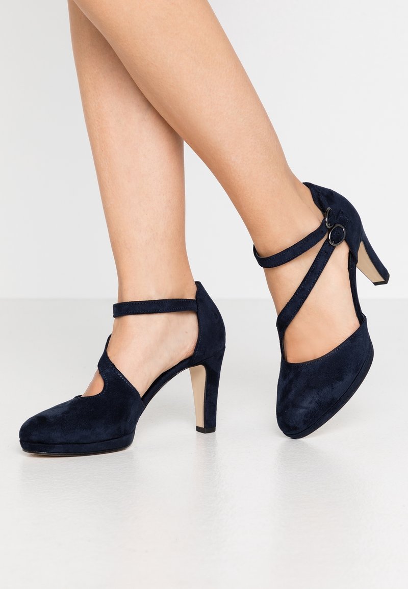 Talons en daim bleu marine avec un bout arrondi, un design découpé et une sangle de cheville avec une boucle circulaire. Talon aiguille pour plus de hauteur.