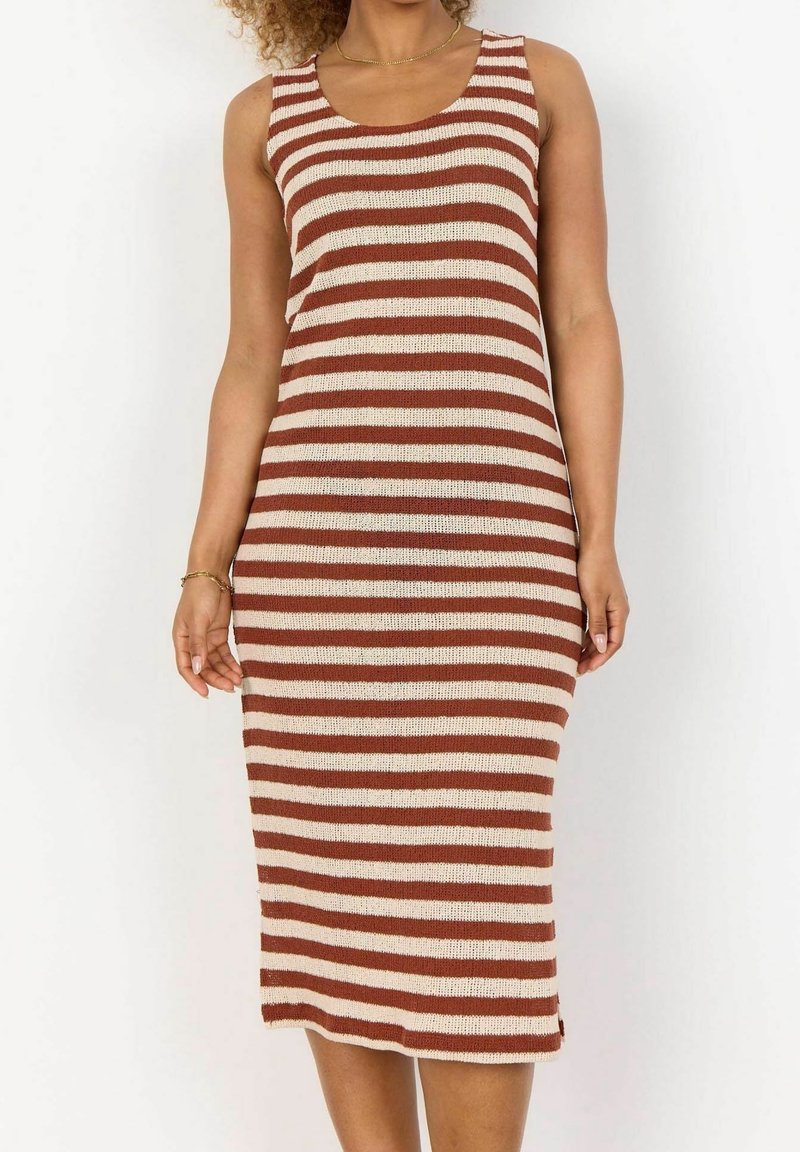 Femme portant une robe tricotée sans manches jusqu'aux genoux, aux rayures horizontales marron et crème, accessoirisée d'un fin collier en or et d'un bracelet.