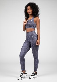 Sportbeha en high-waisted leggings in een gestructureerde donkergrijze stof. Kenmerkt zich door een aansluitend ontwerp en een klein logo op de top en de broek.