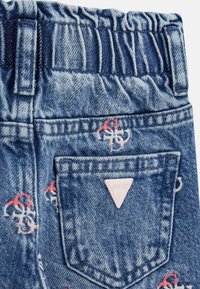 Denimo šortai su gumine juosta, su rožiniu trikampiu logotipu ir daugiaspalviais siuvinėjimais ant mėlynos fono.