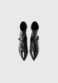 Stivali ankle neri realizzati in pelle liscia, con punte affusolate, chiusura con zip e dettagli decorativi in metallo sulla parte superiore.