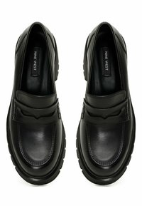 Para czarnych skórzanych loafersów wsuwanych z detalami w szwach i grubymi podeszwami, widziana z góry.