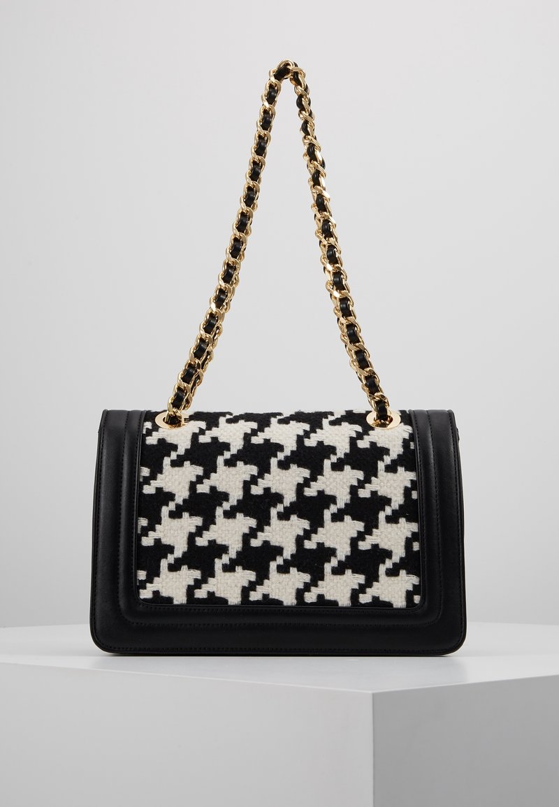 Black and white houndstooth-patterned handbag with a black leather base and a gold and black chain strap. Rectangular shape.