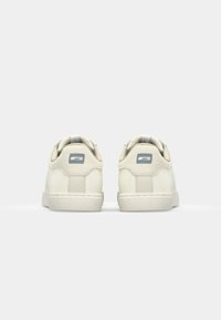Baskets blanches en cuir avec une texture lisse, un col rembourré et des accents logo gris subtils. Dotées d'une semelle en caoutchouc avec une prise texturée.