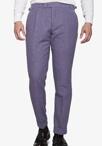 Lila Wollhosen mit taillierter Passform, versehen mit doppeltenFalten, seitlichen Taschen und umgeschlagenen Säumen. Getragen mit einem weißen strukturierten Pullover.