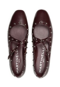 Zapatos Mary Jane de cuero burdeos con punta redonda, detalles de tachuelas y hebilla lateral. La textura suave y el diseño con cortes realzan el estilo.