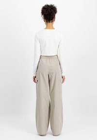 Kuttet hvit langermet topp kombinert med løse beige cargo bukser med sidelommer og elastisk midjebånd.