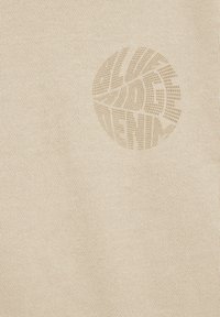 Beige Strickkleidung mit einem strukturierten, runden grafischen Logo. Weicher Stoff mit feinen Rippungen, die ein dezentes, gleichmäßiges Muster erzeugen.