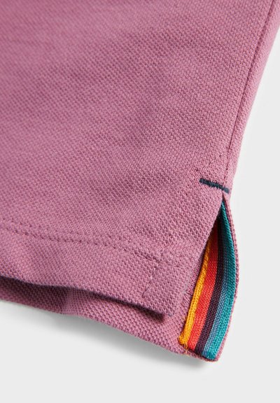 Lilla bomuldsstof med ribbet tekstur, prydet med en sidekant, der afslører multicolore stribede accenter i orange, turkis, rød og sort.