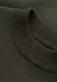 Tessuto di un maglione lavorato a maglia verde scuro con un colletto a coste, texture liscia e leggero luccichio. Vista ravvicinata che mette in risalto la qualità del materiale.