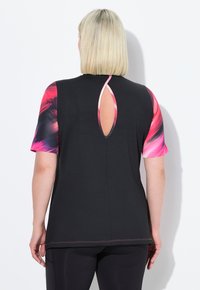 Camiseta negra de manga corta con vibrantes mangas estampadas en rosa y púrpura, con un corte en forma de lágrima en la parte posterior y detalles de costura en contraste.