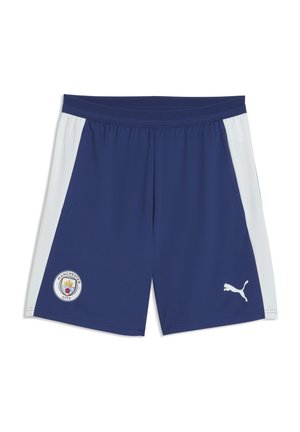Laivastonsiniset urheilushortsit, joissa vaaleanharmaat sivupaneelit, vasemmassa reunassa Manchester Cityn logo ja oikeassa valkoinen Puma-logo.