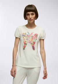 T-shirt bianco a maniche corte con maniche a sbuffo, caratterizzato da un design di farfalla colorata in paillettes sul davanti. Texture di cotone morbido.