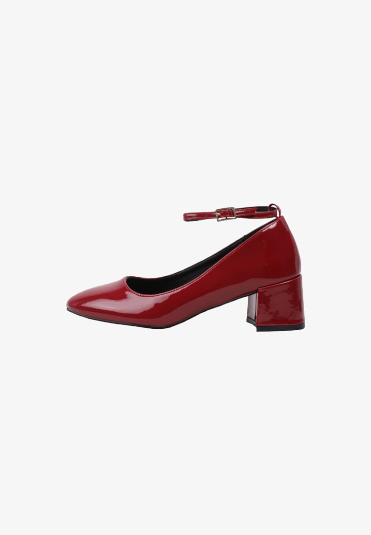 Zapato bajo de tacón cuadrado de charol rojo con punta afilada y tira de tobillo delgada ajustable con hebilla.