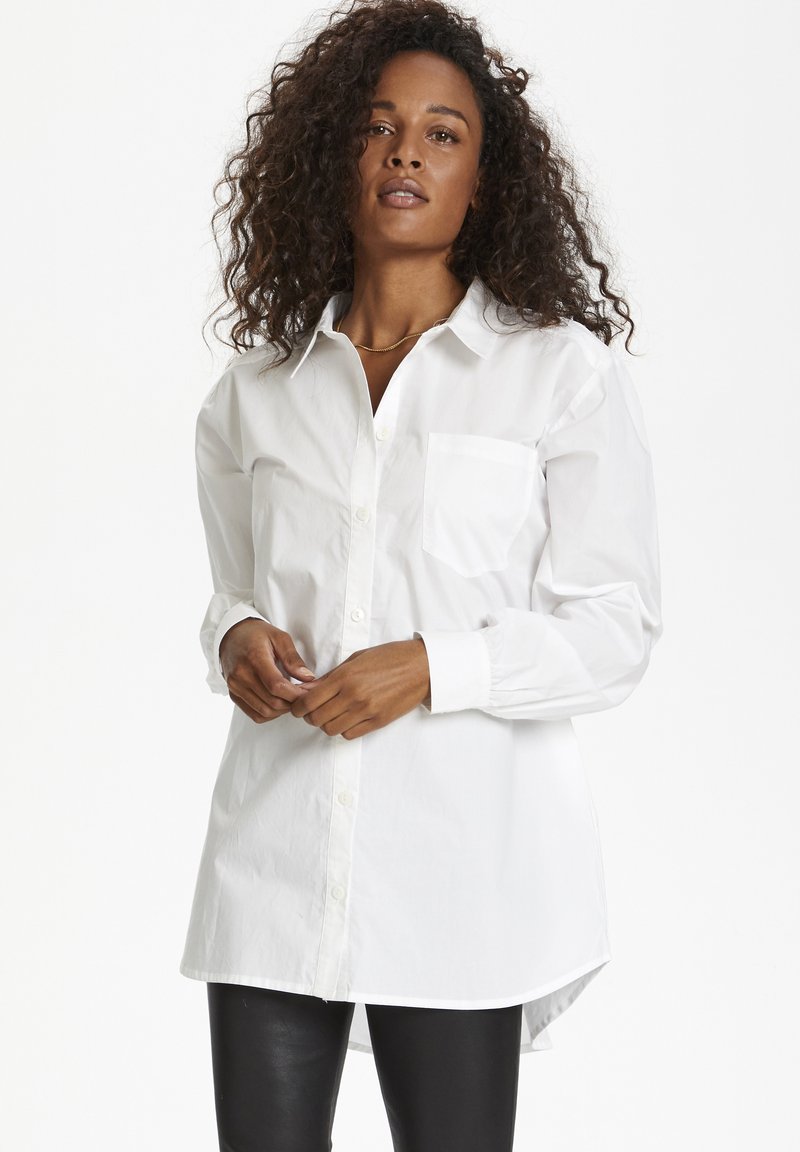 Witte button-up shirt met een kraag, één voordoek, lange mouwen en een gebogen zoom. Gemaakt van lichtgewicht stof met een gladde textuur.