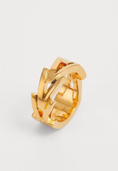 Zelta gredzens ar pārklājošām zigzaga formām, gludu virsmu un pulētu apdari, ar iekšējo iegravējumu zīmola nosaukumam.