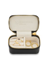 Black zippered jewelry box with beige interior. Contains four gold rings, including a heart-shaped stone design and textured accents.