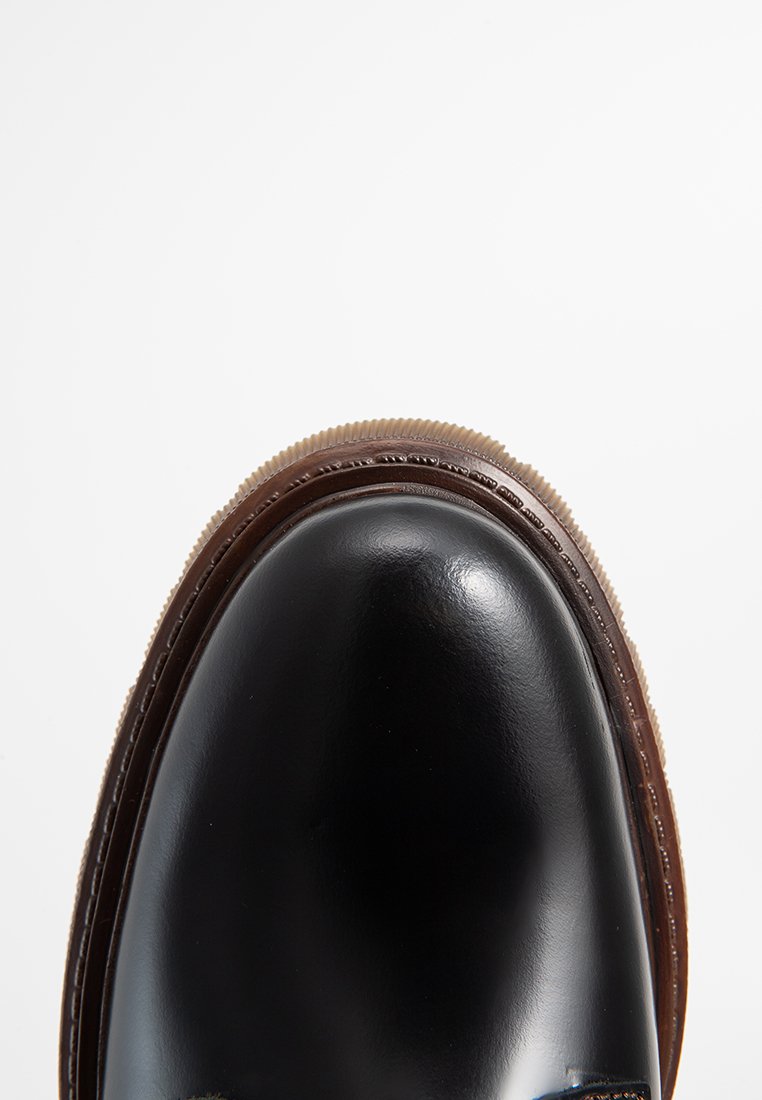 Schwarze Lederschuhe mit glatter Oberfläche, runder Zehenform und kontrastierender brauner Gummisohle. Verfügt über eine Stichdetail entlang der Sohlenkante.