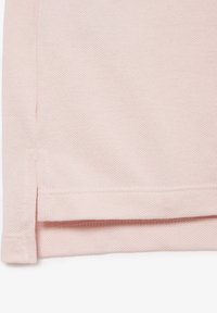 Ljusrosa polo skjorta med texturerat tyg, sidoflikar vid fållen och en ren finish på sömmarna.