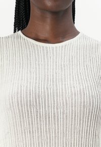 Cream ribbed knit top featuring a round neckline and texture created by vertical stripes. The fabric appears lightweight and airy.