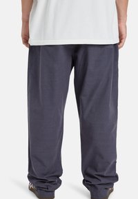 Loszittende donkerblauwe broek gemaakt van lichtgewicht stof. Voorzien van een platte tailleband en licht taps toelopende boorden bij de enkels.