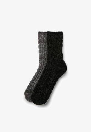 Chaussettes en maille torsadée, présentant une moitié grise et une moitié noire, fabriquées à partir d'un tissu épais et texturé pour la chaleur. Hauteur cheville avec des bords côtelés.